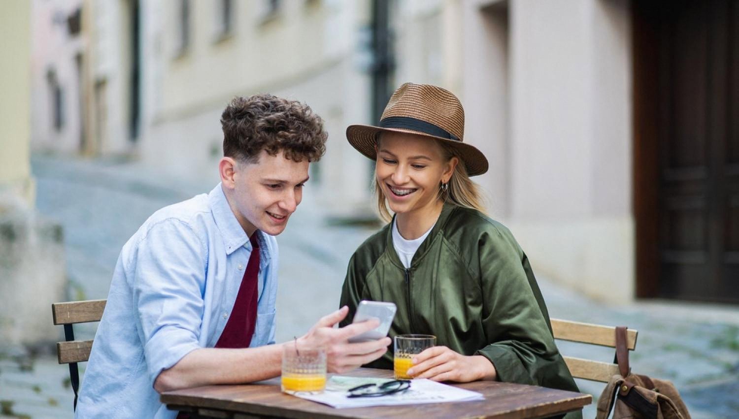 Young couple sitting outside a cafe enjoying cold drinks on a shaded, cooled terrace